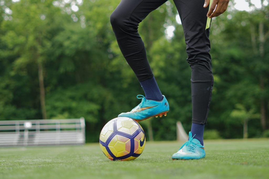 image représentant un footballeur qui pose ses crampons sur un ballon de foot