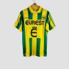Maillot de football vintage du FC Nantes, domicile saison 1995-1996, bandes verticales vertes et jaunes, sponsor Eurest, logo Adidas et écusson du club sur la poitrine.