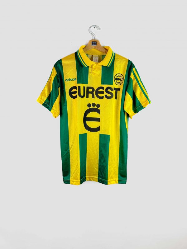 Maillot de football vintage du FC Nantes, domicile saison 1995-1996, bandes verticales vertes et jaunes, sponsor Eurest, logo Adidas et écusson du club sur la poitrine.