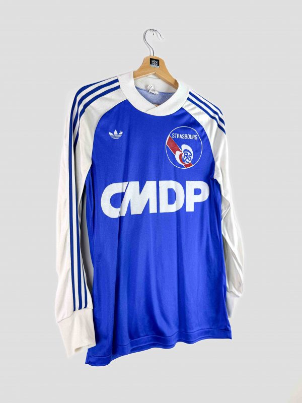 Maillot domicile vintage du RC Strasbourg (saison 1978-1979) posé sur un fond rétro évoquant les années 70