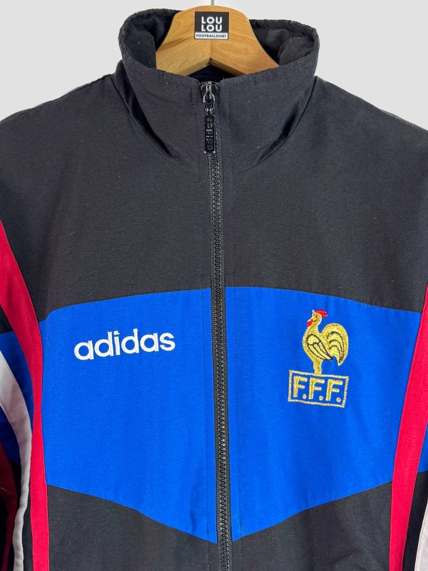 Détail du logo Adidas et de la broderie du coq français sur la veste équipe de France vintage Euro 1996, collection maillot rétro.
