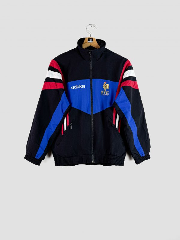 L’équipe de France posant en Angleterre lors de l’Euro 1996, vêtue de la veste équipe de France vintage emblématique de cette époque.