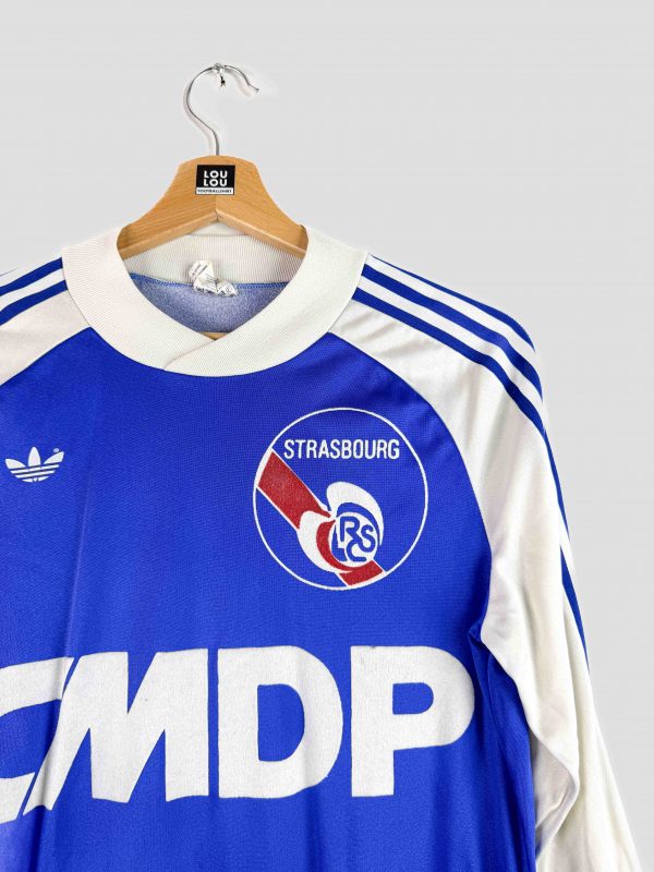 Gros plan sur le maillot Adidas rétro du RC Strasbourg de 1978/1979, aux couleurs bleu et blanc emblématiques